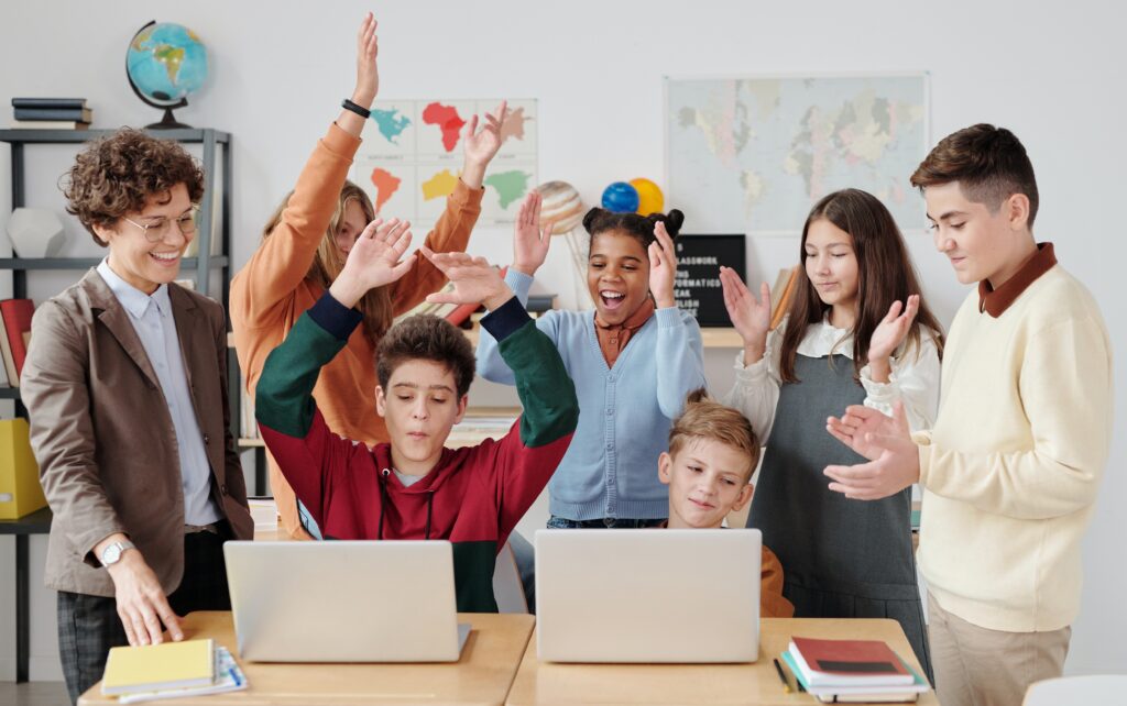 Kids celebrating around laptops