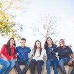 group of people sitting on bench near trees duting daytime