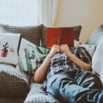 person laying on sofa while reading book